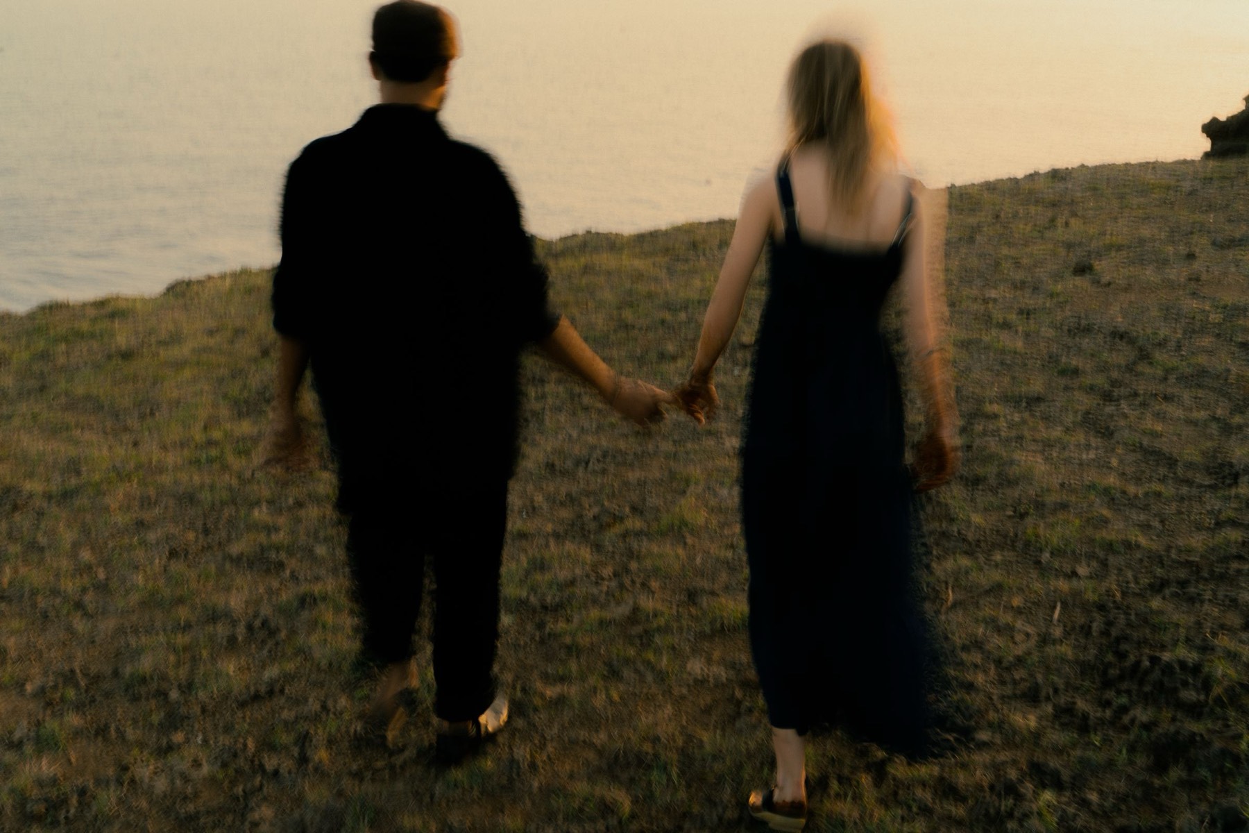 couple marchant main dans la main en extérieur pendant la golden hour, lumière rasante et chaude
